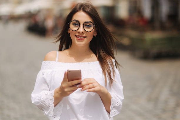 istock Attractive smiling young female texting on cell phone outdoors in city 1022121686