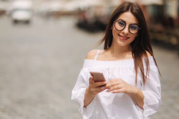 istock Attractive smiling young female texting on cell phone outdoors in city 1022121716