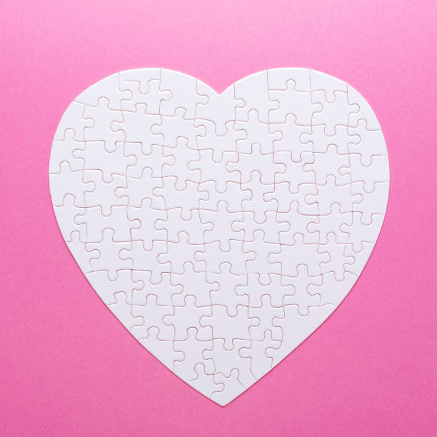istock White puzzle heart on pink background. Top view 1022124640