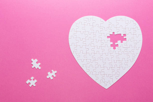istock White puzzle heart on pink background. Top view 1022126712