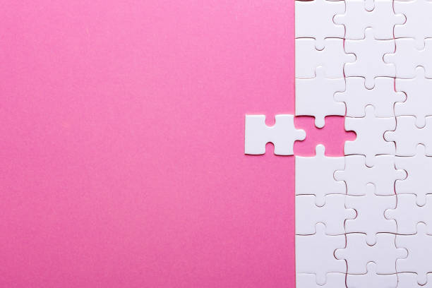 White puzzle on pink background. Top view stock photo