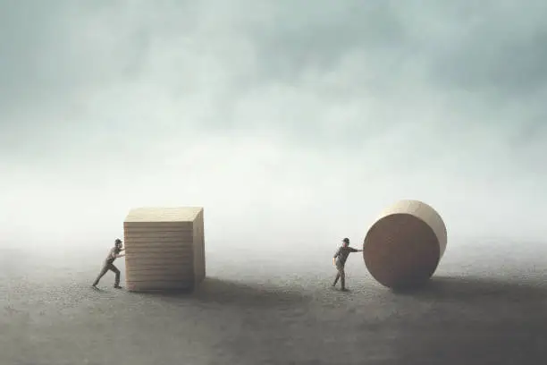 Photo of men pushing different geometric wooden shapes