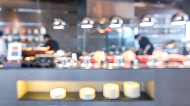 istock Buffet at hotel restaurant interior blur background with blurry open kitchen counter bar of food catering service business with chef staff cooking for breakfast, lunch or dinner meal 1022133966