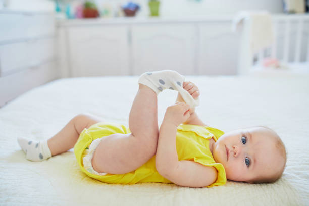 Adorable baby girl removing sock from her foot Adorable baby girl removing sock from her foot. Little child having fun. Infant kid in sunny nursery baby girls stock pictures, royalty-free photos & images