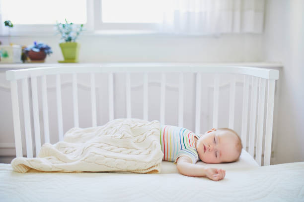 Baby girl sleeping in co-sleeper crib Adorable baby girl sleeping in co-sleeper crib attached to parents' bed. Little child having a day nap in cot. Infant kid in sunny nursery baby mice stock pictures, royalty-free photos & images