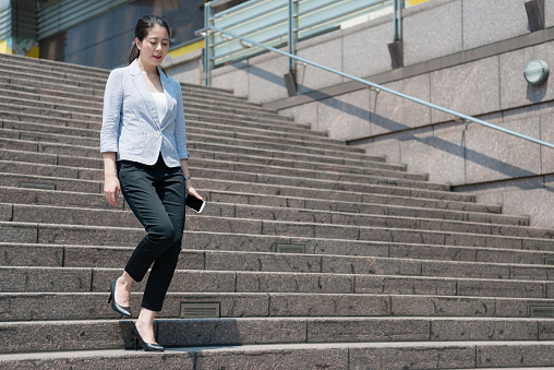 charming business Asian woman walking down on the stair after meeting with her customer.