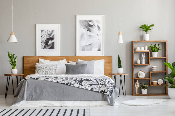 istock Patterned blanket on wooden bed between tables with plants in bedroom interior with posters. Real photo 1022138170
