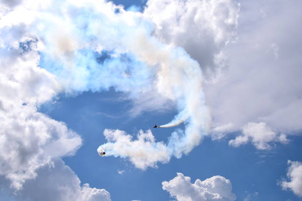 istock Two small helicopters with their rotors on flying through the sky while emmiting a lot of smoke while flying below cloudy summer sky seen during one of trips in Poland 1022153836