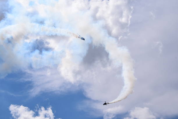 istock Two small helicopters with their rotors on flying through the sky while emmiting a lot of smoke while flying below cloudy summer sky seen during one of trips in Poland 1022153912