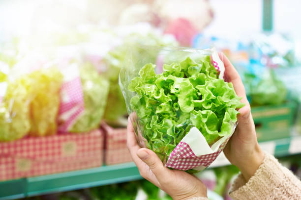 Woman chooses green leaf salad in grocery store