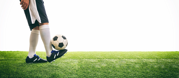 Man controls a soccer ball on the grass. White background and copy space