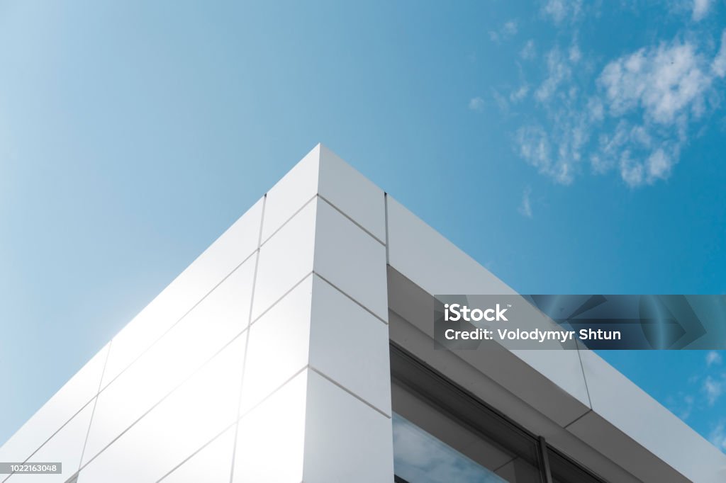 Building with white aluminum facade and aluminum panels against blue sky. Building with white aluminum facade and aluminum panels against blue sky Building Exterior Stock Photo