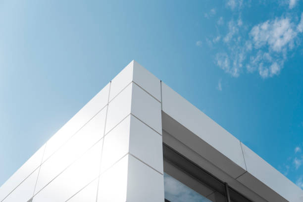 Building with white aluminum facade and aluminum panels against blue sky. stock photo
