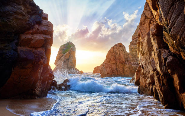 sandstrand zwischen den felsen am sonnenuntergang - water rock landscape cliff stock-fotos und bilder