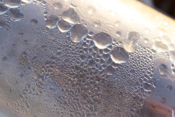PET plastic bottles of cold still and sparking drinking mineral water with blue and red caps float and chill down in ice and water on retail market display, close up, high angle view