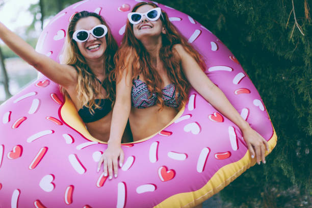 Smiling Girls With Funny Pool Inflatables Outdoors Stock Photo - Download  Image Now - Swimming Pool, Inflatable Swim Ring, Doughnut - iStock