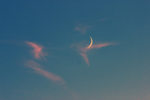 moon on a blue sky with pink clouds