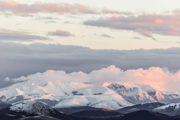 istock Mountain range covered by snow at sunset, with warm, purple shades reflections 1022173090