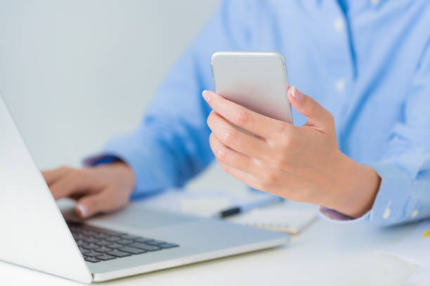 istock Businesswoman hand working with multiple devices using smart phone and typing on laptop keyboard at the office.  Business and finance concepts. 1022173414