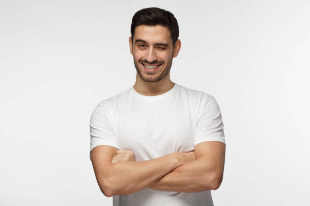 istock Handsome man with crossed arms smiling and winking, looking at camera isolated on gray background 1022174598