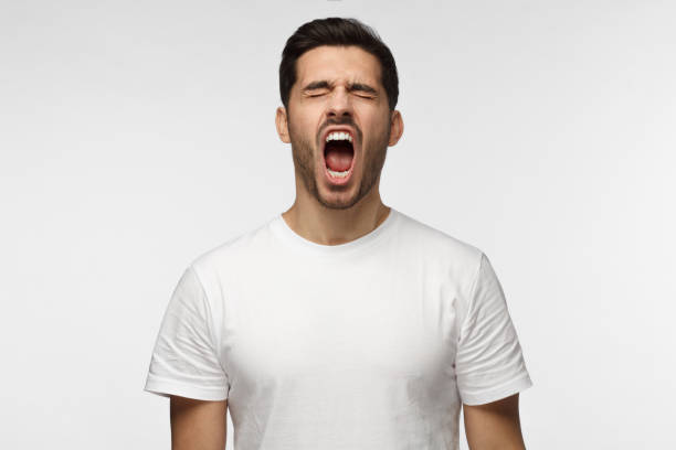 istock Screaming with closed eyes crazy young man in blank white tshirt isolated on gray background 1022174608