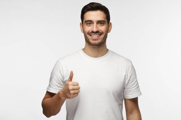 istock Young optimistic man isolated on grey background showing thump up with positive emotions of content and happiness. Concept of satisfaction with quality and recommendation 1022174752