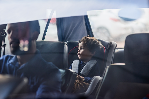 Shot of a little boy sitting in a car seat while his father drives
