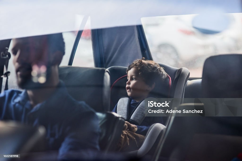 Drive safely with your precious cargo Shot of a little boy sitting in a car seat while his father drives Car Stock Photo