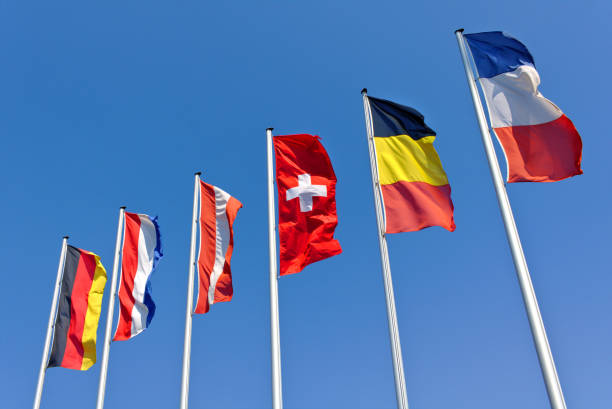 The national flags of Germany, the Netherlands, Austria, Switzerland, Belgium and France flying in front of a blue sky stock photo