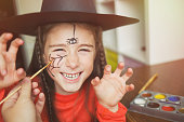 preparation for Halloween. child in a witch outfit doing face painting. cute spider. idea of simple suit, diy