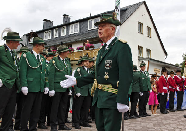 A senior member of a rifle club adresses the ranks of his fellow club members in their traditional green uniforms at a parade at the marksmen's fair stock photo