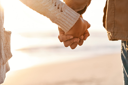 Cropped shot of an unrecognizable couple holding hands on the beach