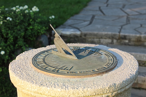 A sundial in the evening with the words “the early bird catches the worm” printed on it.