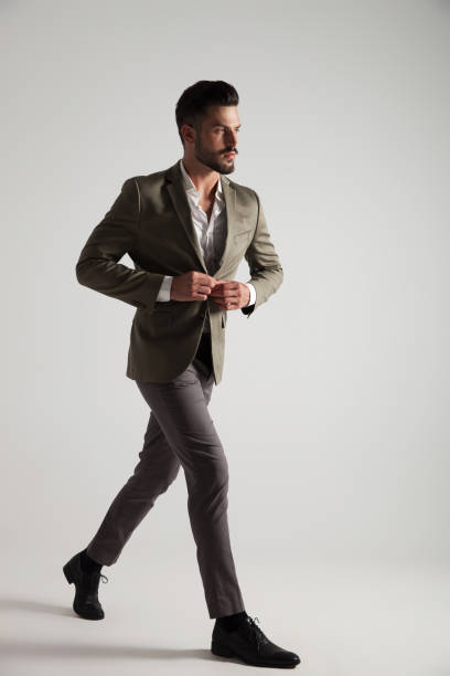 istock handsome young man buttons green suit and walks 1022225030
