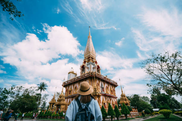 젊은 여자는 푸 켓 타운, 태국에서 와트 카오 또는 카오 사원에서 아름 다운 탑으로 여행 하는 배낭 여행자. 태국 푸 켓에서에서 가장 인기 있는 태국 사원입니다. - thailand 뉴스 사진 이미지