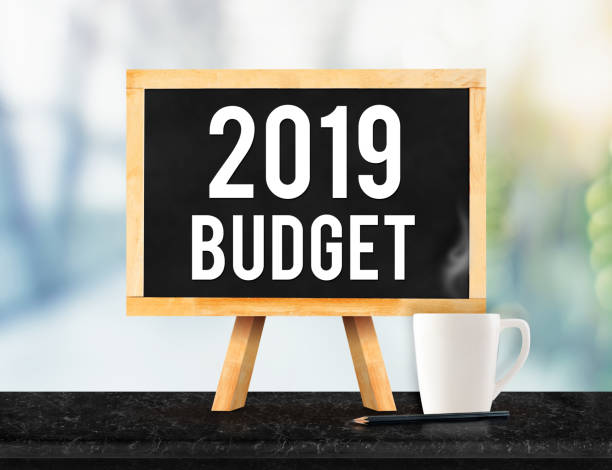 2019 budget on blackboard with easel on black marble table with coffee cup and pencil on blurred office building New year business plan concept