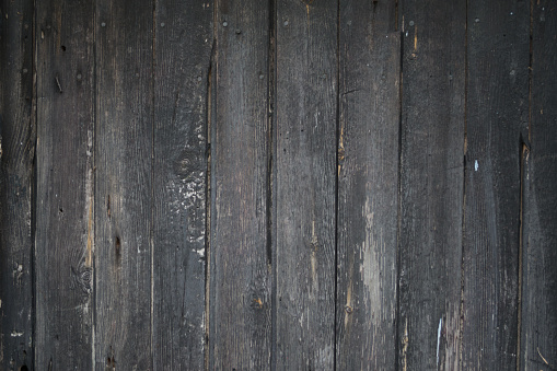Grungy peeling flaking black paint on grey wooden boards closeup wallpaper backdrop