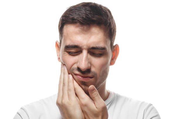 istock Tooth ache concept. Young man feeling pain, holding his cheek with both hands, suffering from bad toothache, having painful expression. 1022250196