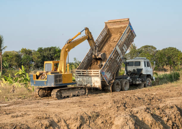 istock Yellow backhoe digging soil fill in rear truck 1022254988