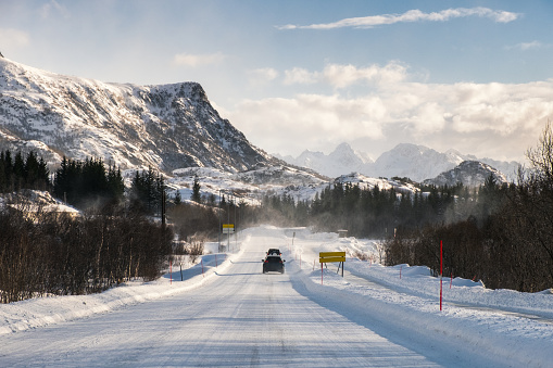 Car driving on snowy road with mountain range in winter at rural