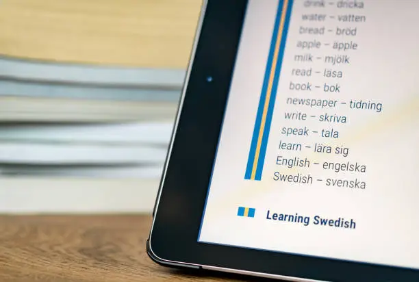 Photo of Learning Swedish using a tablet with books in the background.