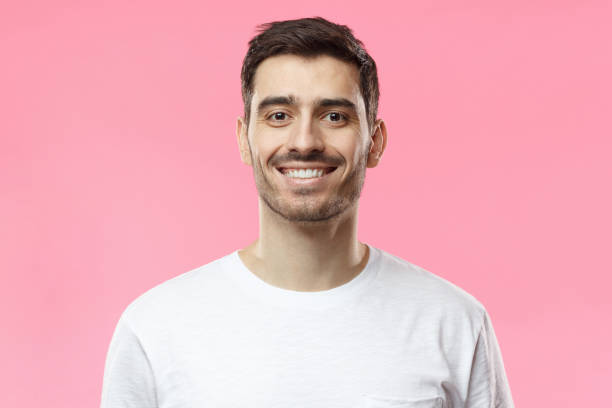 close up portrait of smiling handsome man in white t-shirt isolated on pink background - t shirt shirt pink blank imagens e fotografias de stock