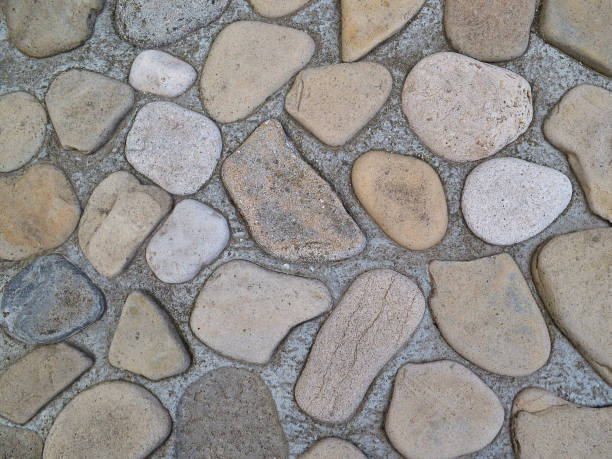 istock Decorative wall paved with flat round shape sea stones  almost completely submerged in the cement 1022264232