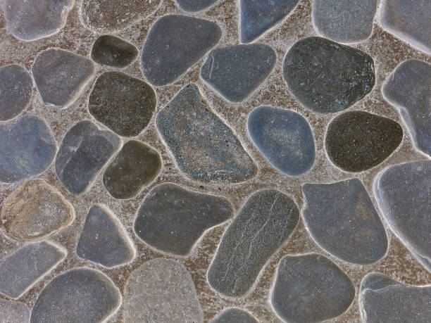 istock Decorative wall paved with flat round shape sea stones  almost completely submerged in the cement 1022264268