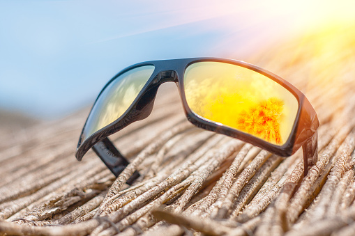 sunglasses on a straw beach umbrella, a concept of tropical relaxation