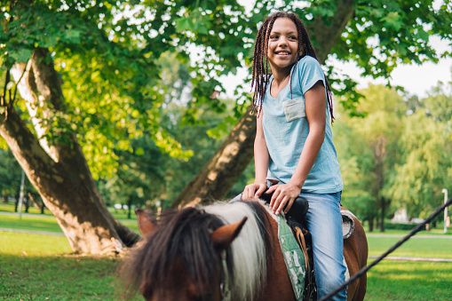Happy young girl riding a horse