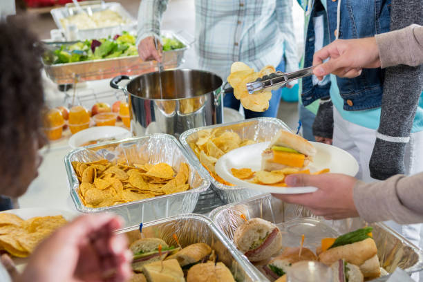 Volunteers serve the homeless in soup kitchen Unrecognizable group of volunteers serve a meal to people in a soup kitchen. community center food stock pictures, royalty-free photos & images
