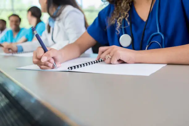 Photo of Unrecognizable medical student writes in class workbook