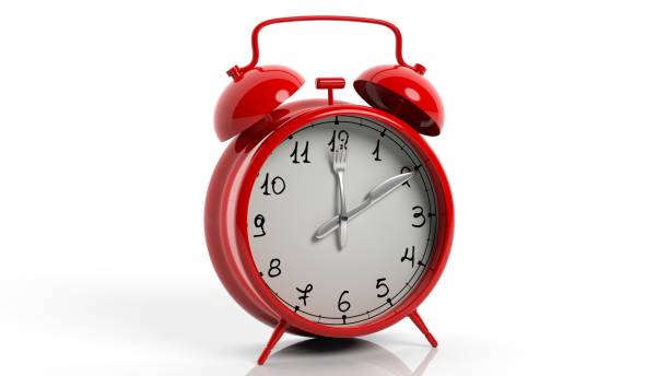 istock Retro red alarm clock with knife and fork as poinets, isolated on white background. 1022284012