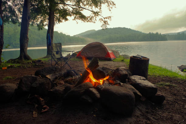Campfire outside of tent and campsite on a lake in the Adirondack Mountains. Summer Camp ground on a misty morning in upstate new york tent photos stock pictures, royalty-free photos & images